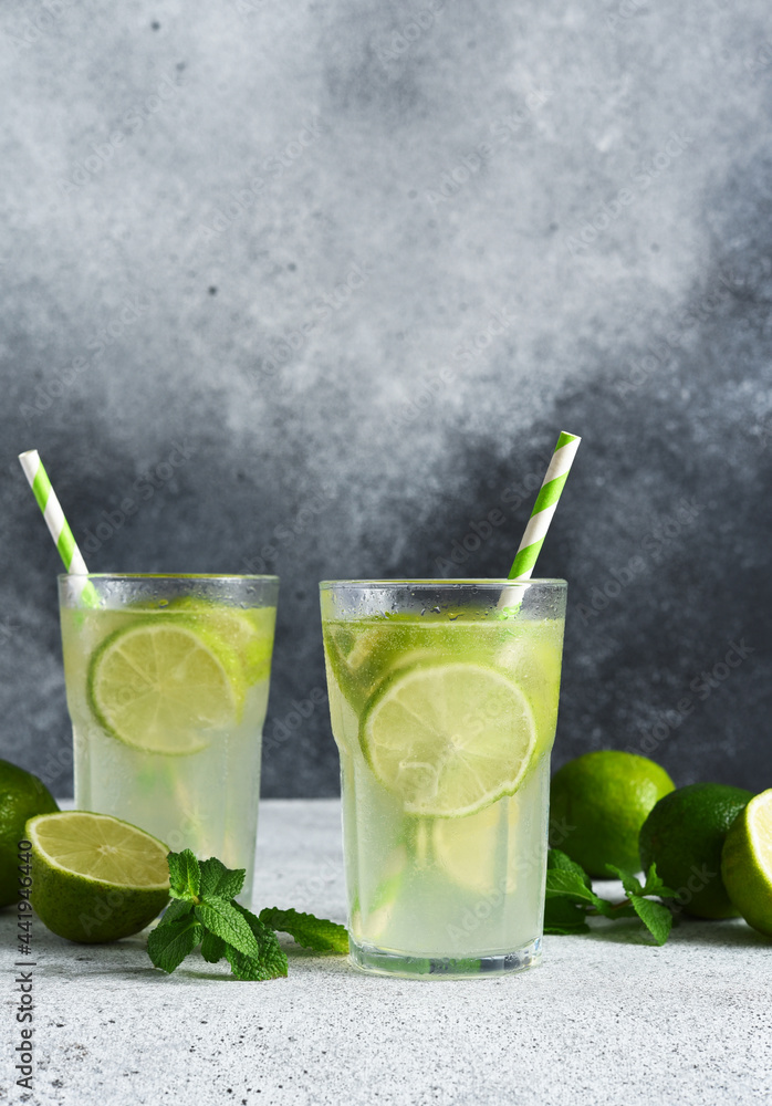 Fototapeta premium Iced tea with lime. Cold lemonade with lime on a concrete background.