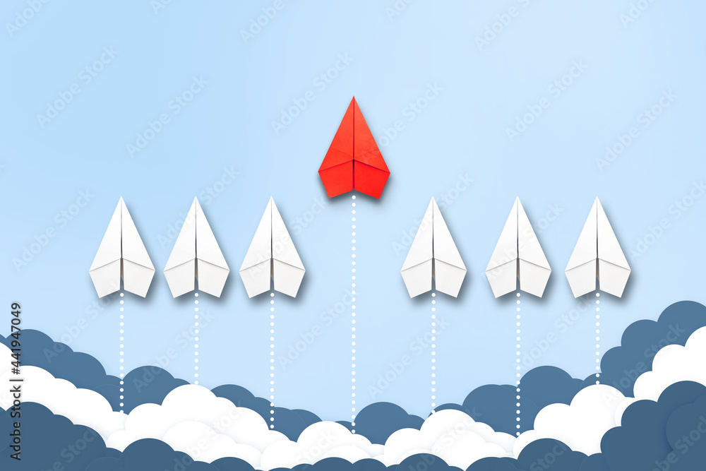 Red paper plane flying in a different direction than the white ones. Cloudy sky. Copy space. The concept of innovative solutions, creativity. Business. Lifestyle. Red paper plane flying in a different direction than the white ones. Cloudy sky. Copy space. The concept of innovative solutions, creativity. Business. Lifestyle.