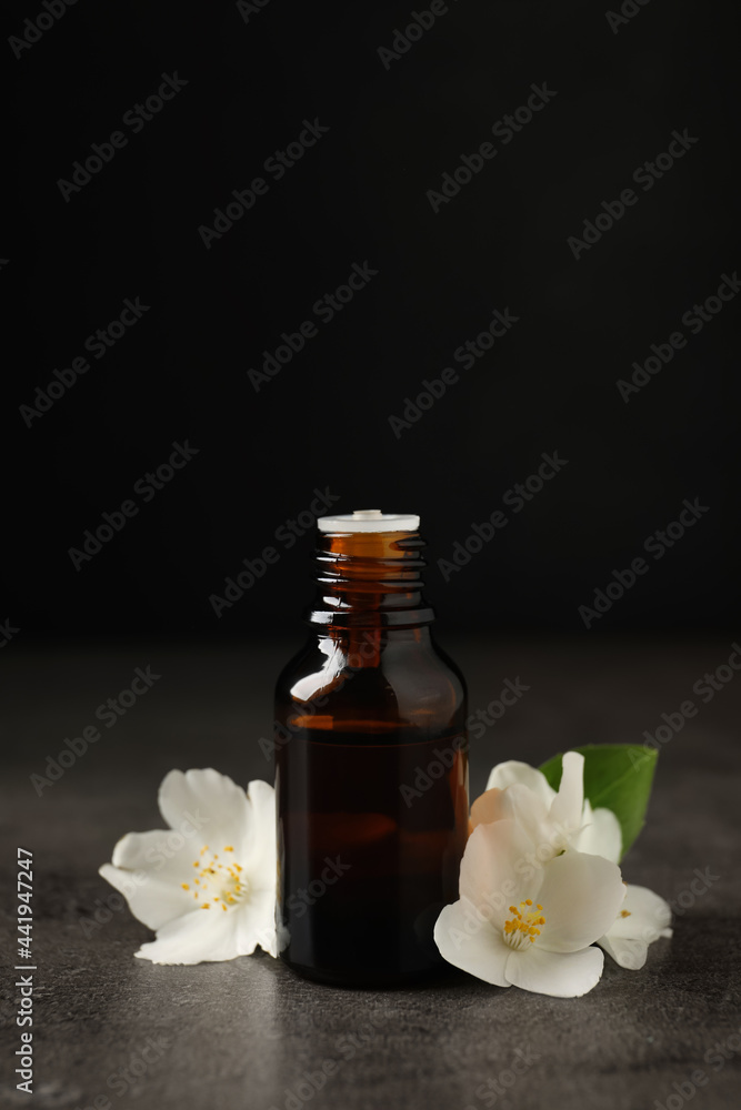 Essential oil and jasmine flowers on grey table Essential oil and jasmine flowers on grey table