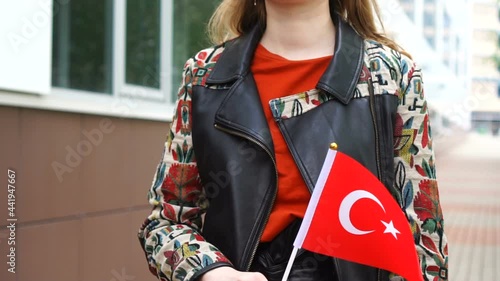 Unrecognizable woman holding Turkish flag. Girl walking down street with national flag of Turkey