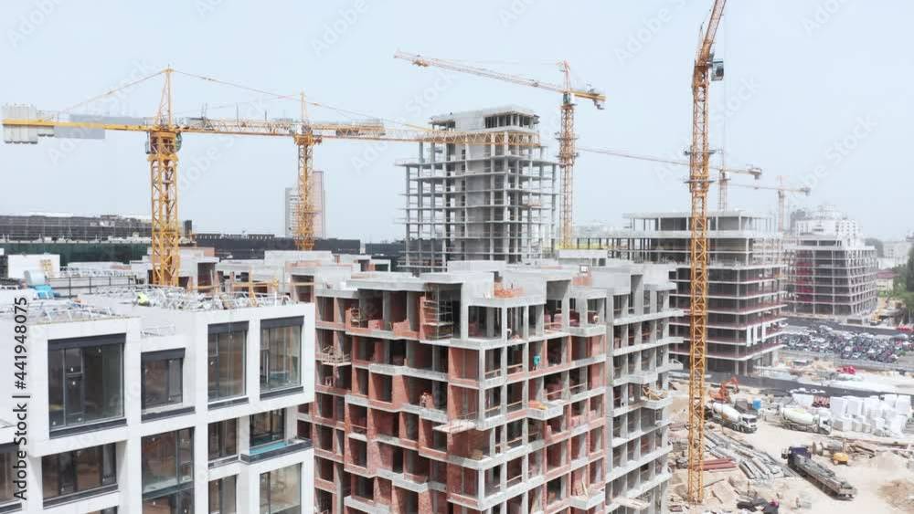 Aerial Flight Over a New Constructions Development Site with High Tower Cranes Building Real Estate. Heavy Machinery and Construction Workers are Employed. Urban Construction Site, Aerial View Aerial Flight Over a New Constructions Development Site with High Tower Cranes Building Real Estate. Heavy Machinery and Construction Workers are Employed. Urban Construction Site, Aerial View