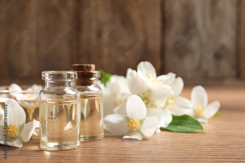 Jasmine essential oil and fresh flowers on wooden table, space for text Jasmine essential oil and fresh flowers on wooden table, space for text