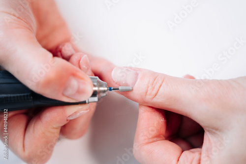 Home manicure. In the photo, a woman removes the top layer of the nail plate using a nail cutter.