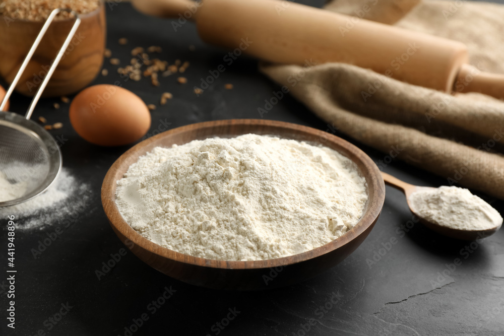 Wooden bowl of flour on black table Wooden bowl of flour on black table