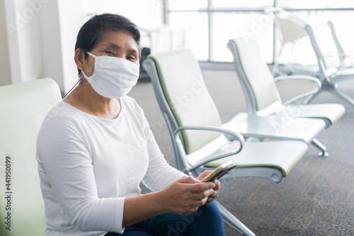 Asian COVID-19 protection situation in New Normal wear medical face mask protection virus corona pandemic outbreak for traveling  using Smartphone searching check-in flight timetable airport terminal
