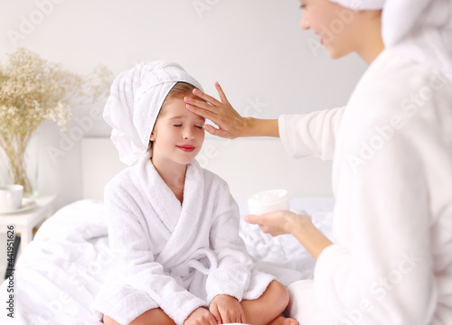 Mother smearing cream on face of daughter