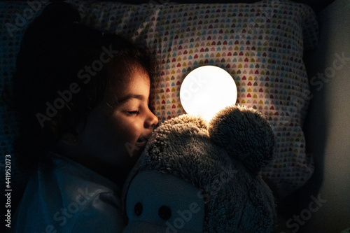 Little girl trying to fall asleep with a light so she won't be afraid of the dark
