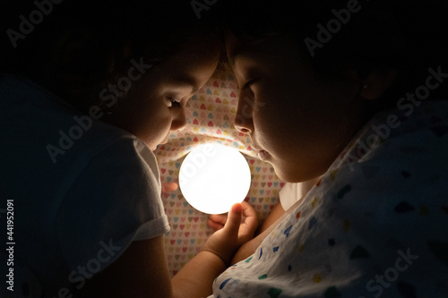 Fotografi Two sisters sleeping by a light to chase away their fears of the dark
