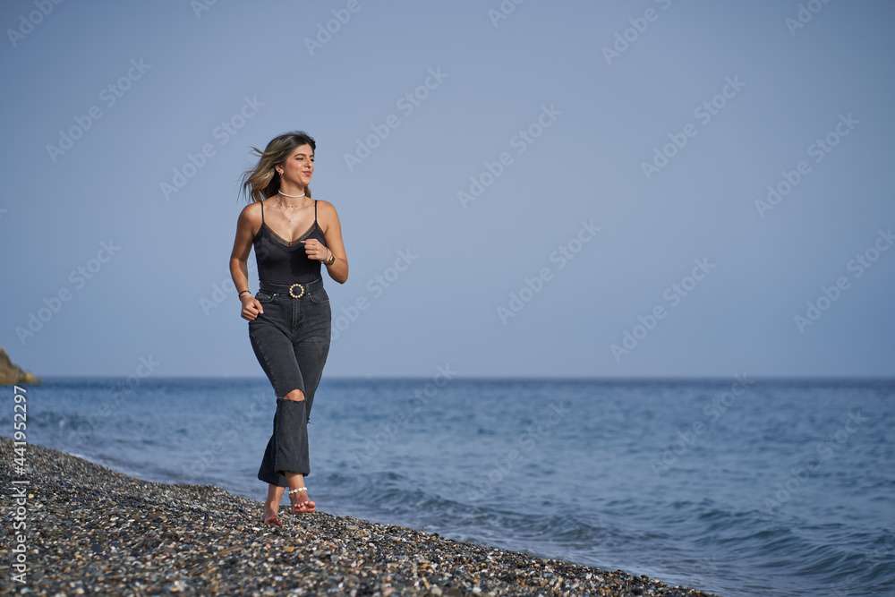 young woman running along the beach dressed in black