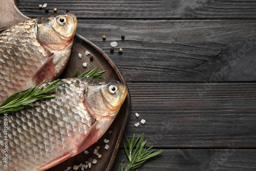 Photography Fresh raw crucian carps and ingredients on black wooden table, above view with space for text