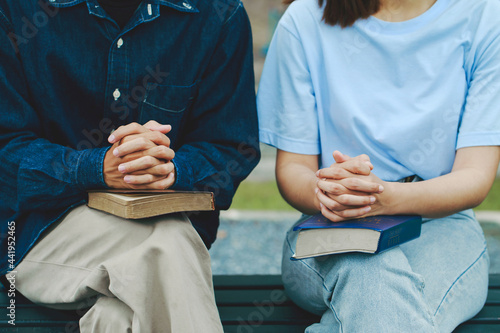 Christians and Bible study concept..Two Christianity sitting around a wooden table with the holy bible and praying to God together. faith, spirituality, worship, and religion.