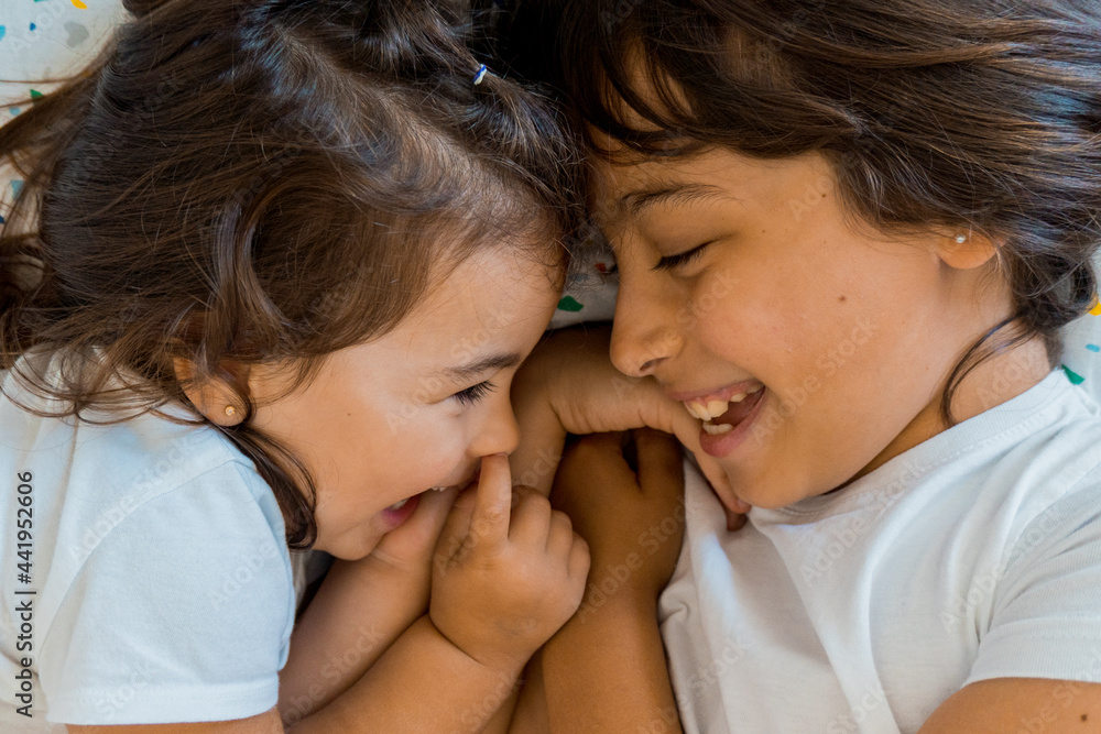 Close-up of two sisters facing each other, sharing laughs and confidences. Close-up of two sisters facing each other, sharing laughs and confidences.