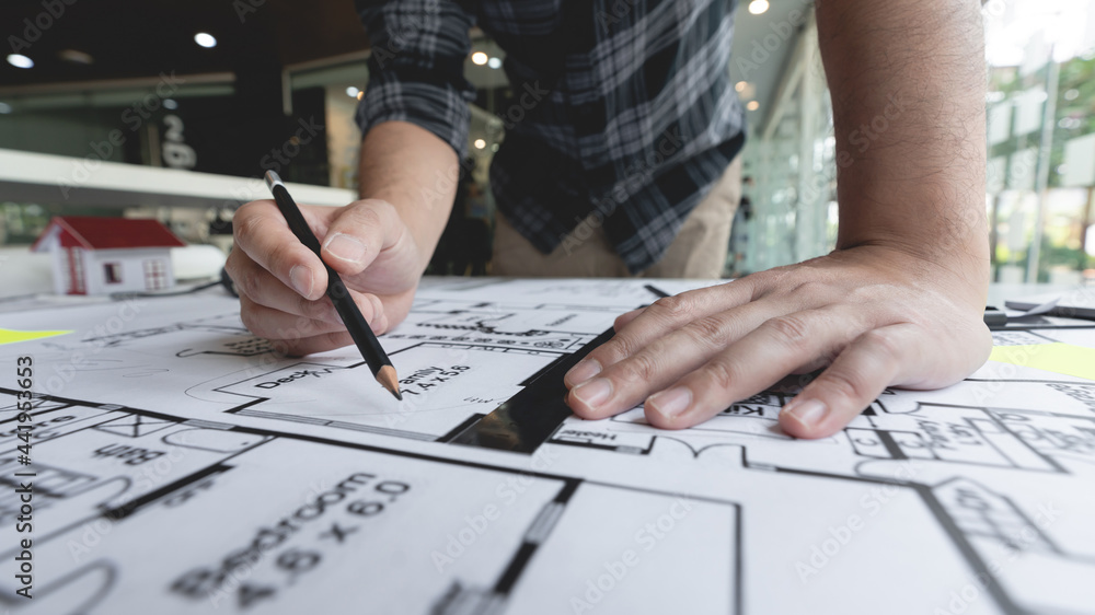 A male architect measuring and marking the scale ratio of sizes of a complicated blueprint A male architect measuring and marking the scale ratio of sizes of a complicated blueprint