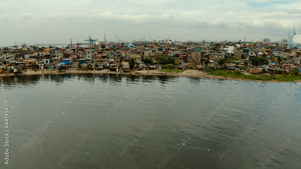 Slums near the port with shacks of local residents and the river bank littered with garbage from above. Manila, Philippines.