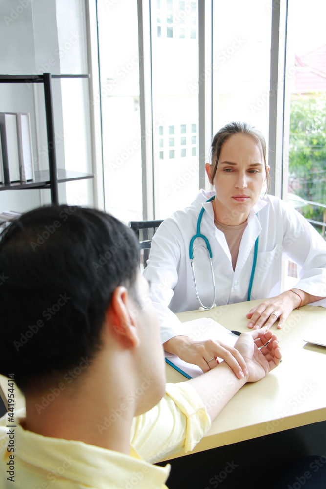 Obraz premium Caucasian Female Psychiatrist or neurologist is counseling and touching pulsation of patient for treatment asian man in clinic at hospital. Major depressive disorder patients and healthcare Concept.