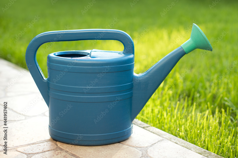 Large blue watering can for gardening and caring for grass in the country Large blue watering can for gardening and caring for grass in the country
