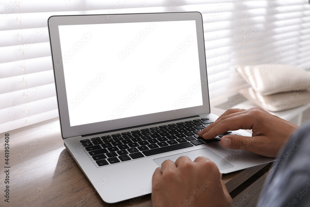 Man with modern laptop at wooden table indoors, closeup. Space for design Man with modern laptop at wooden table indoors, closeup. Space for design