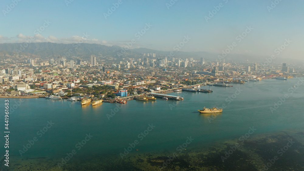 Panorama of Cebu City, seaport with ships and ferries and modern skyscrapers and residential buildings. Philippines.