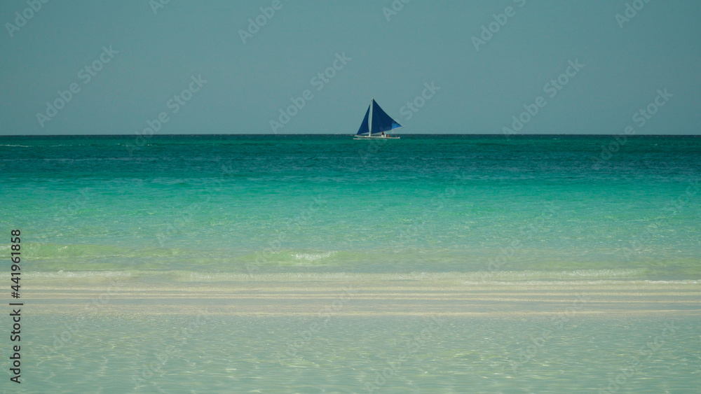 Obraz premium Seascape: tropical beach and sailing yacht in crystal clear turquoise water. Summer and travel vacation concept. Boracay, Philippines