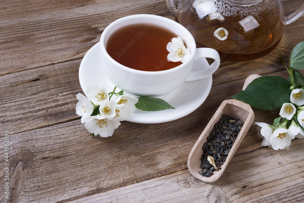 Green tea with jasmine in cup and teapot on wooden rustic table Green tea with jasmine in cup and teapot on wooden rustic table