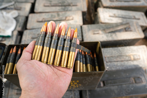 Action of people hand is holing a row of sniper rifle or heavy machine caliber from bullet cartridge. Military weapon object photo.