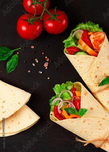 Tortilla wraps, grilled Mexican chicken with vegetables, burritos, on a black table, without people,
