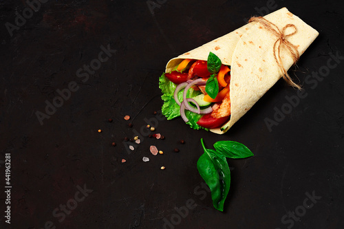 Tortilla wraps, grilled Mexican chicken with vegetables, burritos, on a black table, without people,