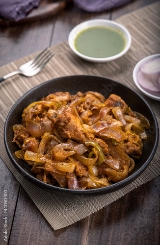 Chilli chicken is a popular Indo-Chinese dish, served on a plate on wooden background 