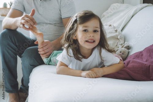 фотографія Father plays with little daughter 2-4 on couch