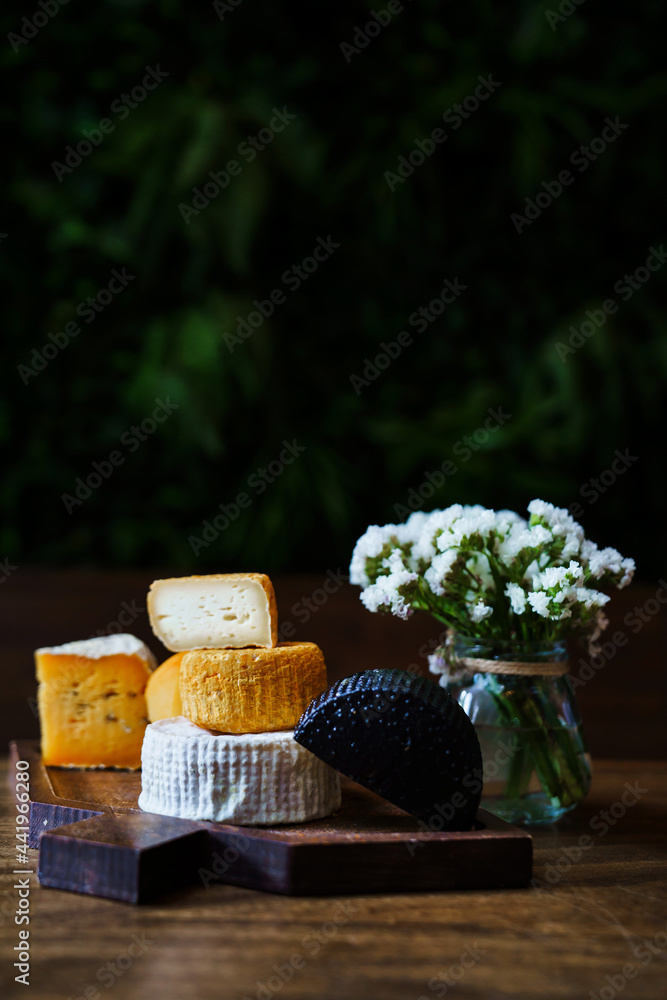 assorted cheese heads on cutting board with a small bouquet of flowers assorted cheese heads on cutting board with a small bouquet of flowers