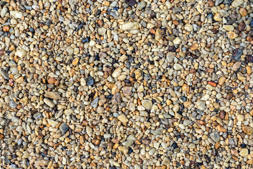 Shiny sea pebbles lie in an even layer on the beach. Natural background and texture of the stone.