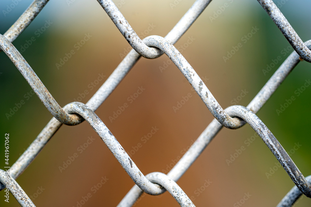 A close up picture of a rusty wire fence with colorful background