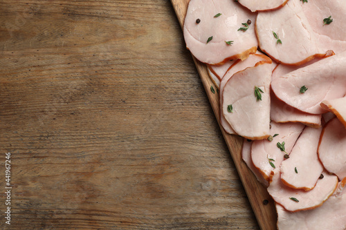 Delicious sliced ham with thyme and peppercorns on wooden table, top view. Space for text