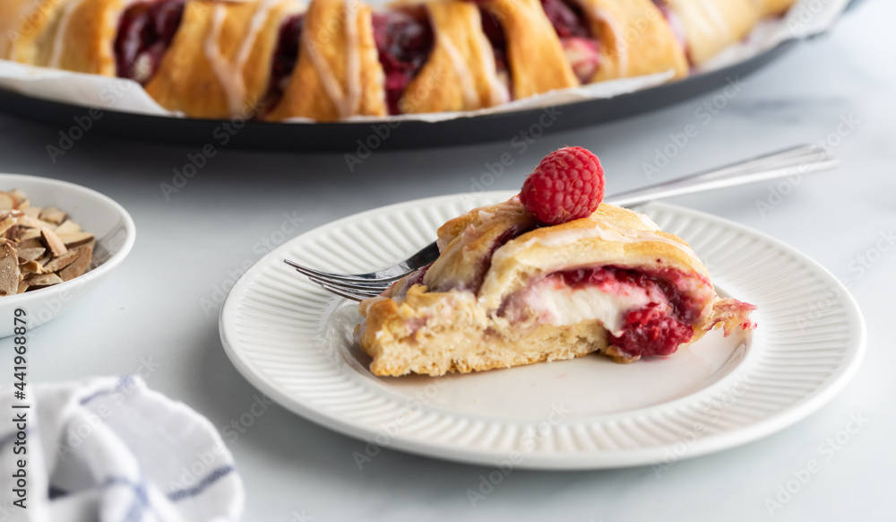 Close up view of a slice from a raspberry crescent ring, ready for eating.