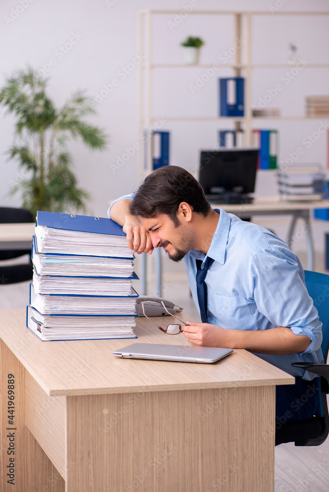 Young male employee and too much work in the office Young male employee and too much work in the office