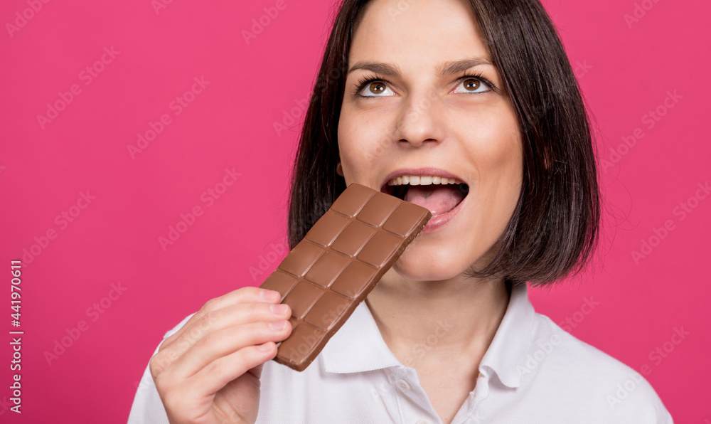 Beautiful young woman bites a bar of chocolate. Beautiful young woman bites a bar of chocolate.
