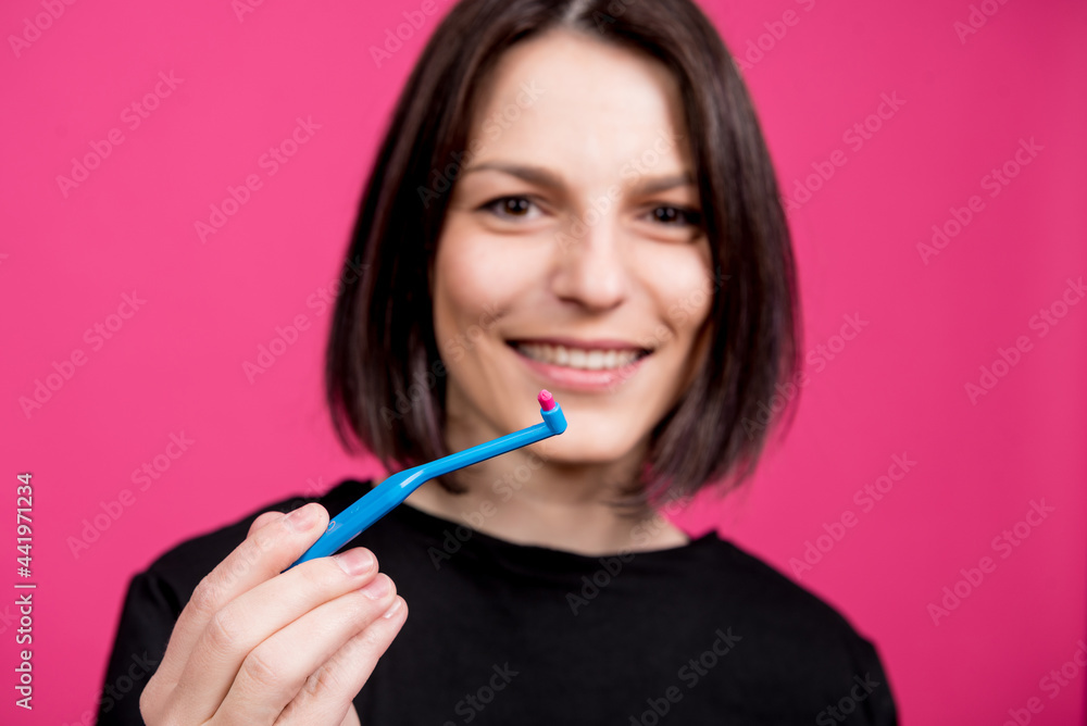 Beautiful happy young woman with single tufted toothbrush on blank pink background Beautiful happy young woman with single tufted toothbrush on blank pink background