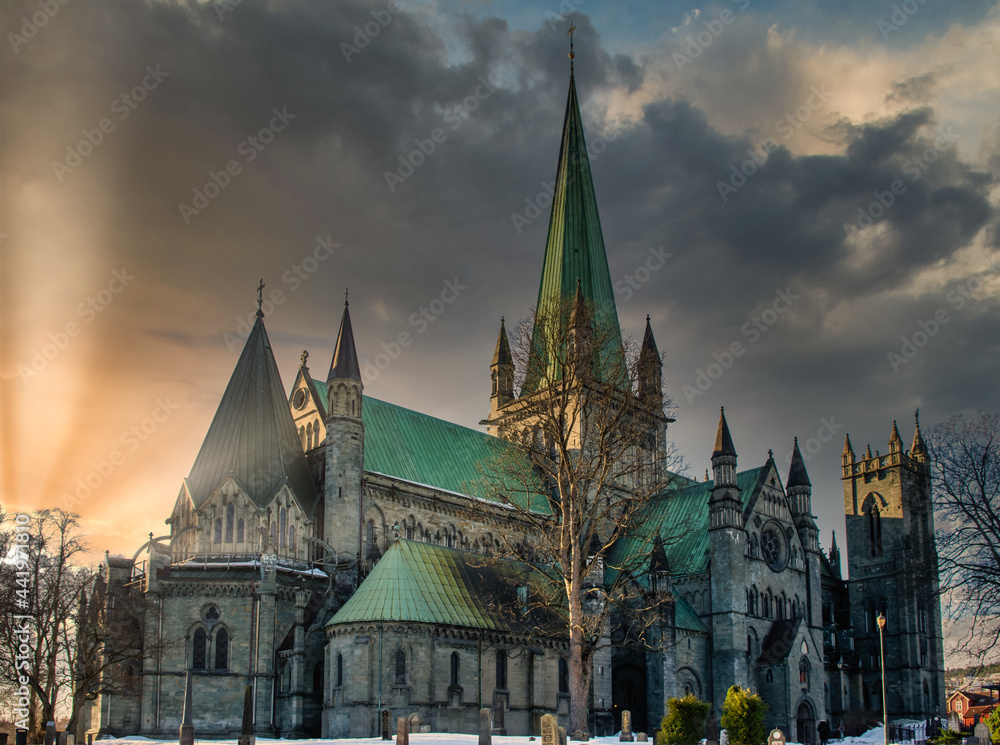 Nidaros Cathedral in Trondheim, Norway during sunset with sun flare and cloudy sky