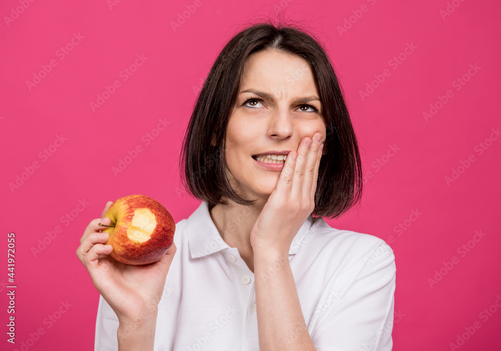 Beautiful young woman bites a big apple and has a toothache Beautiful young woman bites a big apple and has a toothache