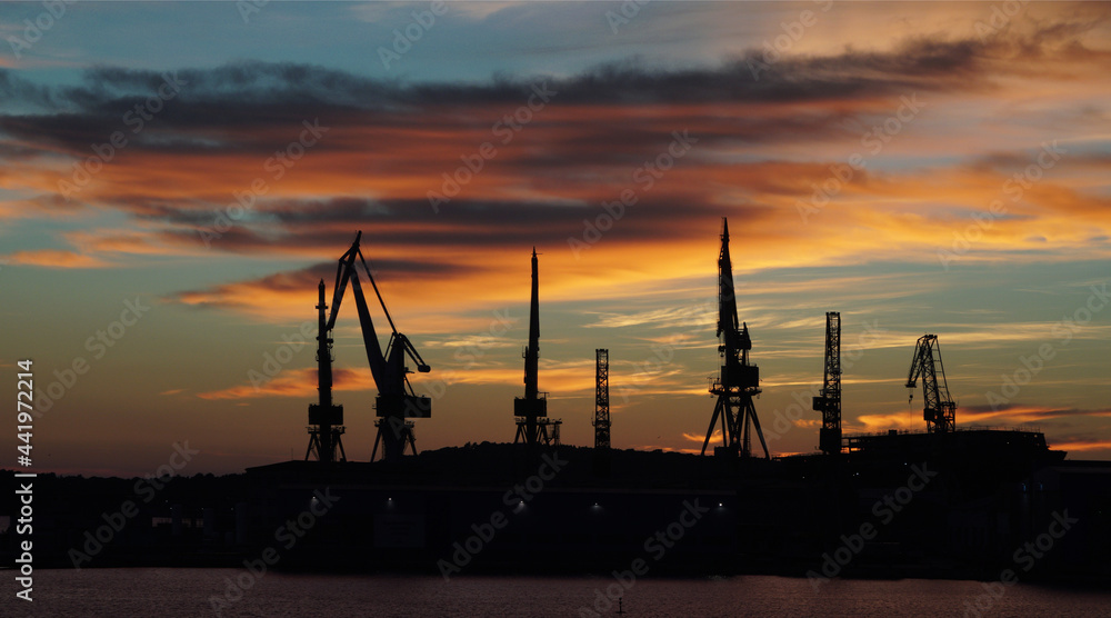 Tall cranes silhouettes at sunset, Pula, Croatia Tall cranes silhouettes at sunset, Pula, Croatia
