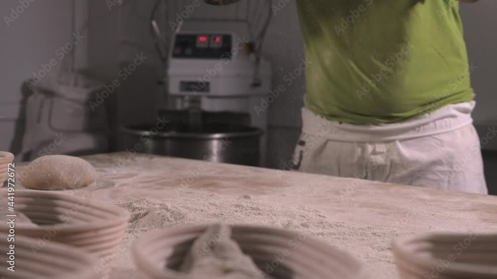 Slow motion of hands of baker chef applying flour on dough. Making bread using traditional recipe Slow motion of hands of baker chef applying flour on dough. Making bread using traditional recipe
