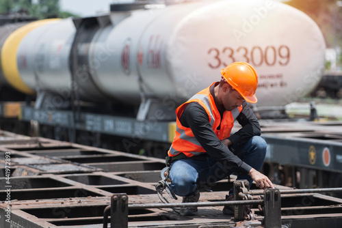 worker on the station. worker on the railway. worker sitting on bogie with oil tank on background.
