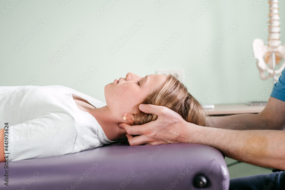 Massage therapist performing cranial sacral therapy on a female child ...