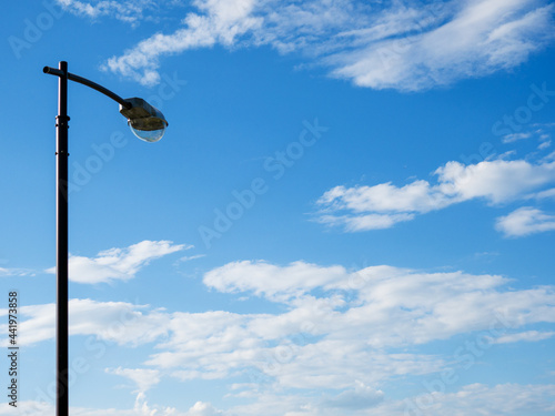 The street lighting pole against the background of a blue sky with clouds.