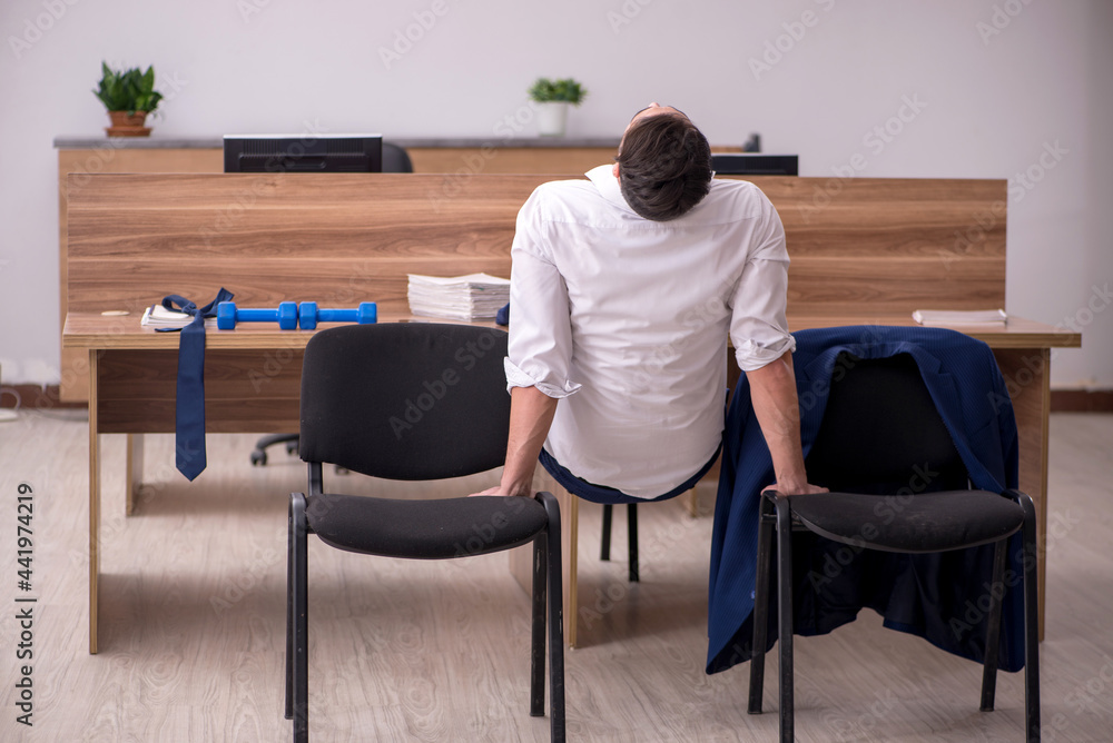 Young businessman employee doing sport exercises at workplace Young businessman employee doing sport exercises at workplace