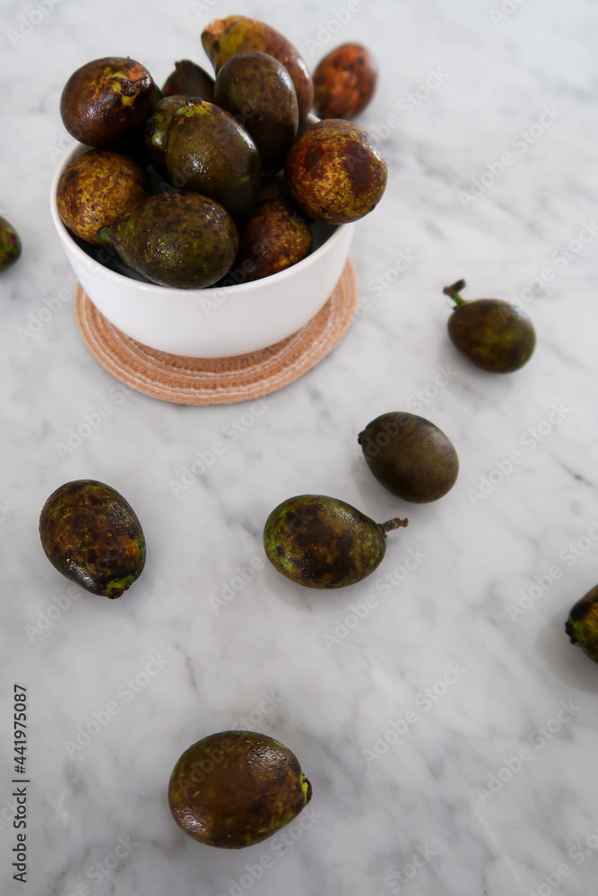 Obraz premium Matoa fruits from Papua Indonesia in the bowl on the marble table. Unique and rare fruit.