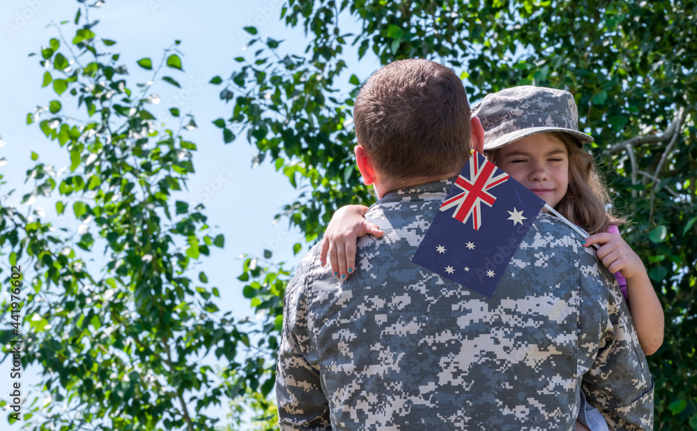Reunion of soldier from Australia with family, daughter hug father. A girl holds the flag of Australia in her hand