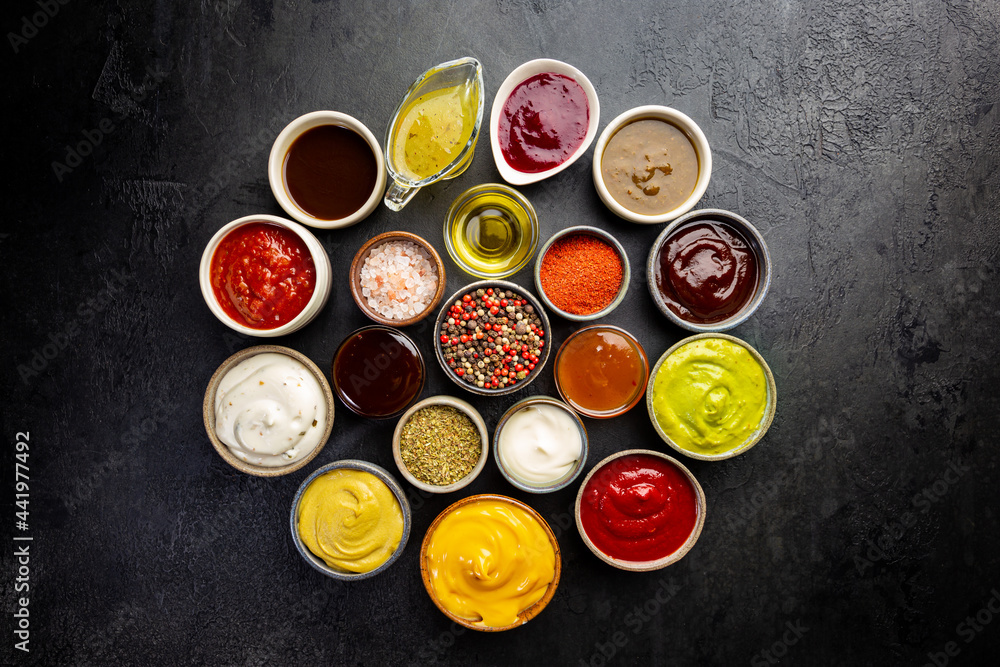 Set of different bowls of various dip sauces, on dark background, top view Set of different bowls of various dip sauces, on dark background, top view