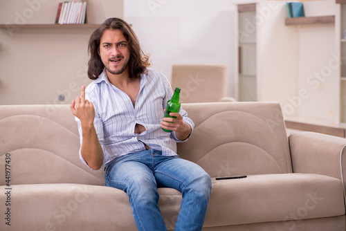 Young man drinking alcohol at home