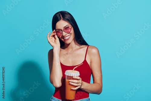 Attractive young woman looking at camera and smiling while standing against blue background